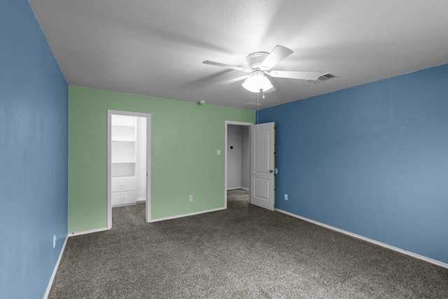 unfurnished bedroom featuring a textured ceiling, a ceiling fan, visible vents, baseboards, and dark carpet