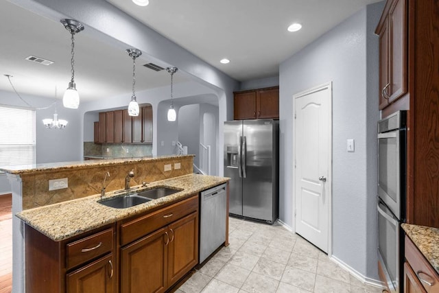 2202 Kuykendall Dr, Georgetown, TX 78626 - kitchen featuring appliances with stainless steel finishes, decorative backsplash, pendant lighting, light stone counters, and an island with sink