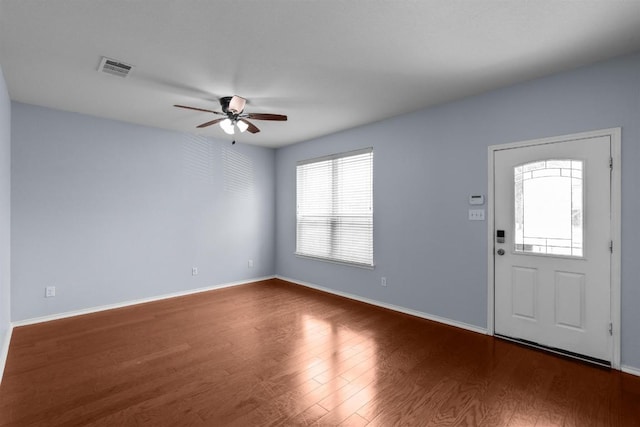 foyer featuring a ceiling fan, visible vents, baseboards, and wood finished floors