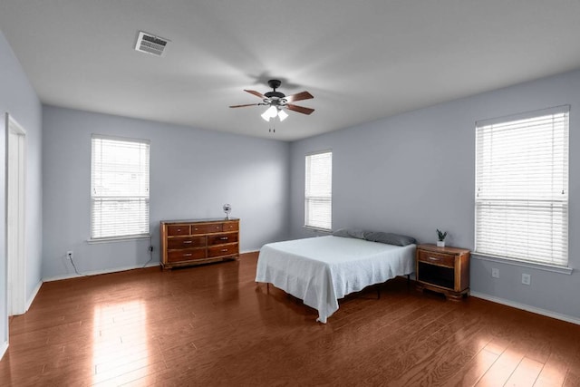 bedroom featuring visible vents, ceiling fan, baseboards, and wood finished floors