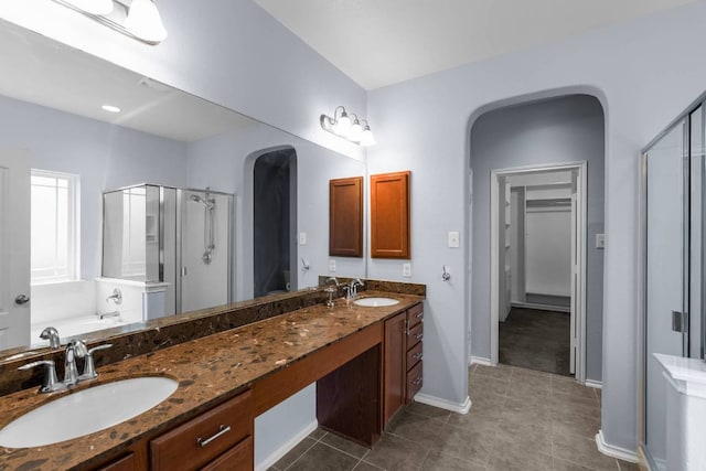 bathroom featuring a stall shower, double vanity, a sink, and tile patterned floors