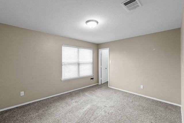 carpeted spare room featuring baseboards, visible vents, and a textured ceiling