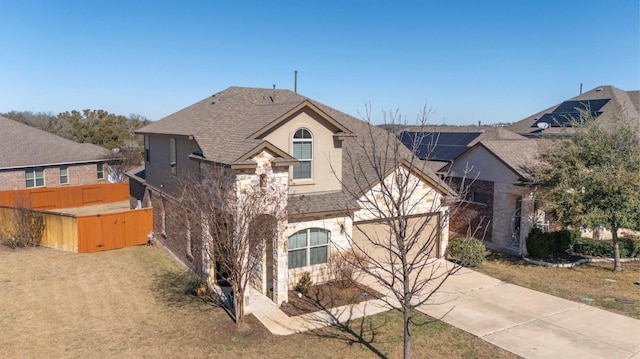 view of front of property featuring roof with shingles, fence, driveway, and stucco siding