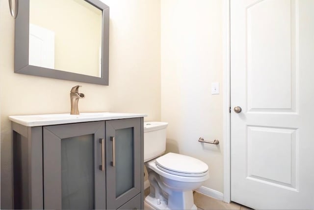 half bathroom featuring tile patterned flooring, baseboards, vanity, and toilet