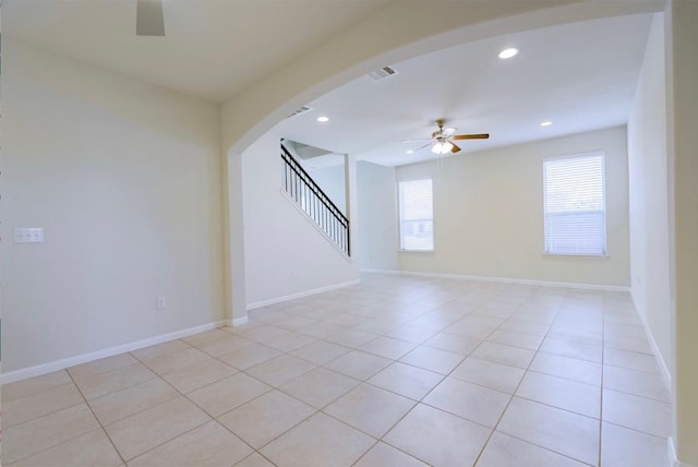 unfurnished room with arched walkways, ceiling fan, stairway, and recessed lighting