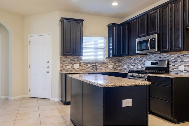 kitchen with stainless steel appliances, arched walkways, light tile patterned flooring, and tasteful backsplash