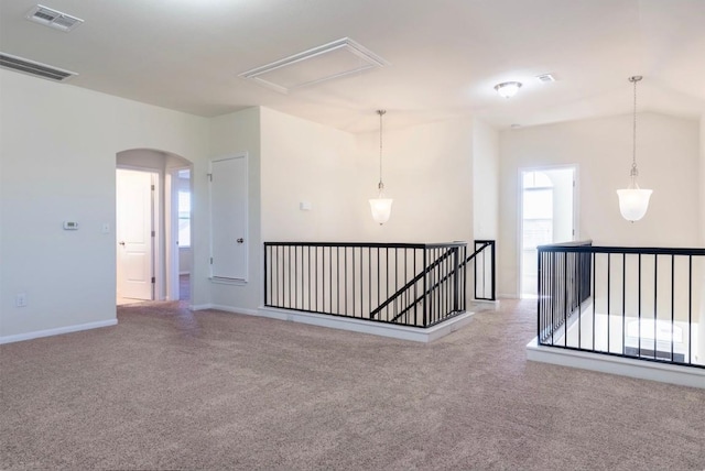 carpeted empty room with arched walkways, visible vents, attic access, and baseboards