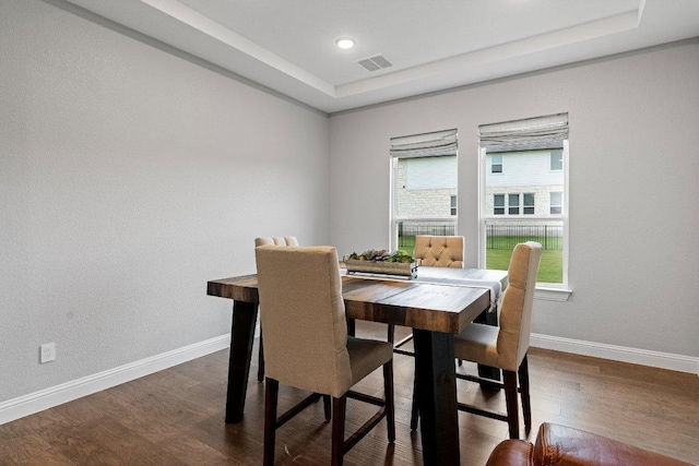 dining area with dark wood-style floors, a raised ceiling, visible vents, and baseboards