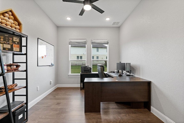 office space featuring ceiling fan, a textured wall, visible vents, baseboards, and dark wood finished floors