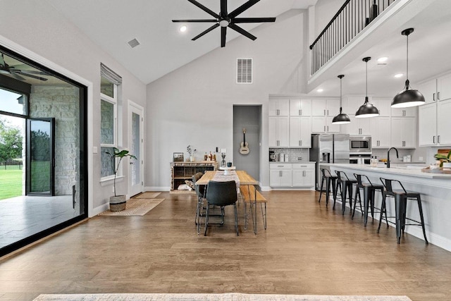 kitchen featuring visible vents, a ceiling fan, light wood-style flooring, stainless steel appliances, and a kitchen bar