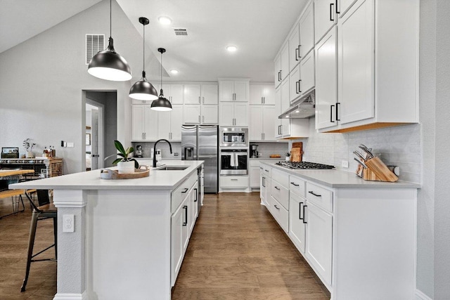 kitchen with under cabinet range hood, a breakfast bar, a sink, appliances with stainless steel finishes, and tasteful backsplash