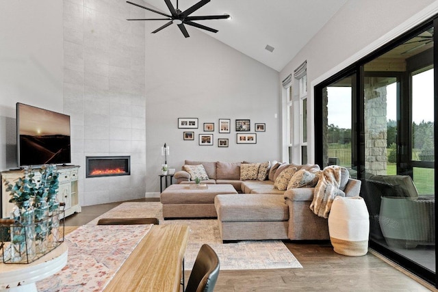 living room with high vaulted ceiling, visible vents, a fireplace, and wood finished floors