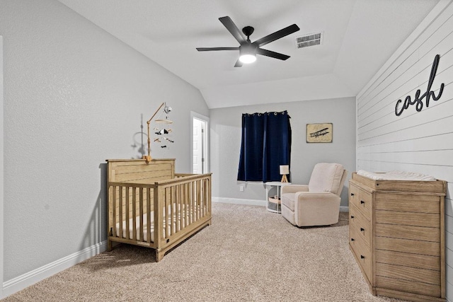 carpeted bedroom featuring a nursery area, lofted ceiling, visible vents, and baseboards