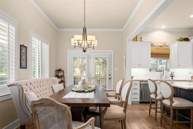 dining area featuring a chandelier, light wood finished floors, and crown molding