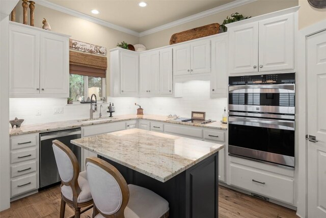 2216 Garden Ct, San Marcos, TX 78666 - kitchen with stainless steel appliances, white cabinetry, a kitchen bar, a center island, and crown molding