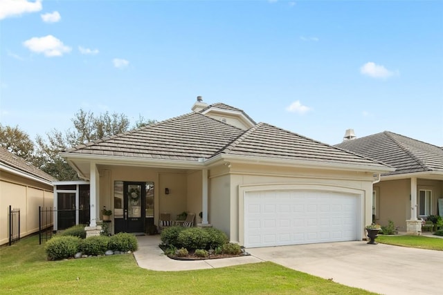 view of front of home featuring an attached garage, concrete driveway, french doors, a tiled roof, and stucco siding