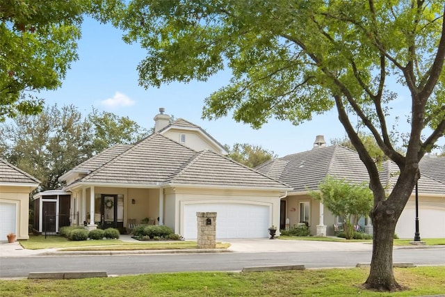 view of front of property with a garage, a chimney, concrete driveway, and a tiled roof