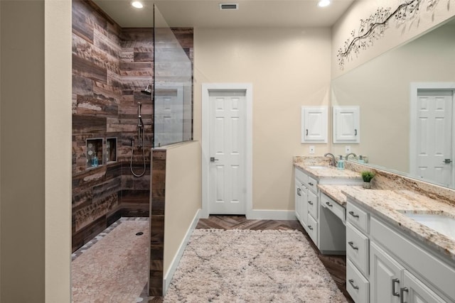 full bath with a sink, double vanity, walk in shower, and baseboards