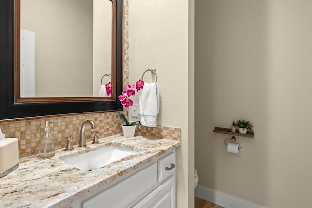 half bath with toilet, baseboards, backsplash, and vanity