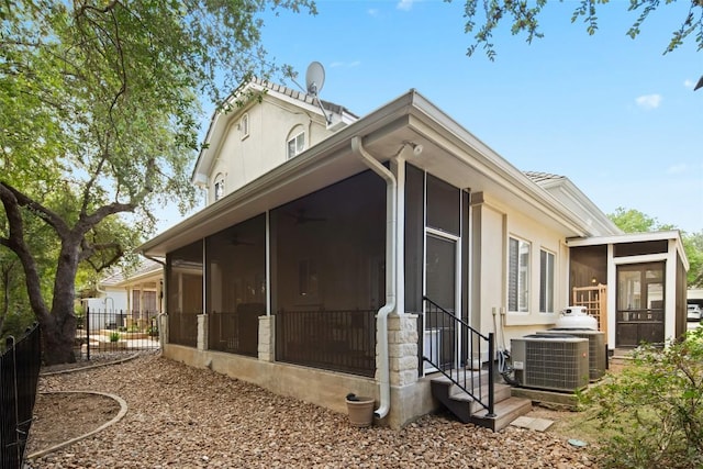 view of side of property with central AC unit, fence, and a sunroom