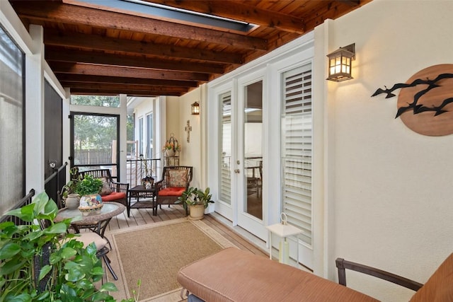 sunroom featuring beamed ceiling, a skylight, and wood ceiling