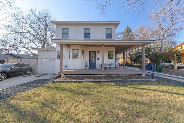 view of front facade with a porch, a garage, a front yard, and driveway