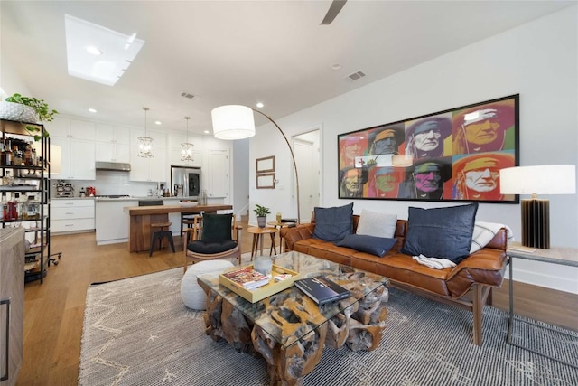 living room with recessed lighting, visible vents, and light wood-style flooring