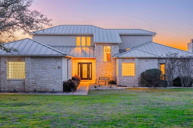 view of front of home featuring a standing seam roof, metal roof, and a yard