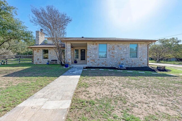 4113 Rimrock Dr, Lago Vista, TX 78645 - view of front facade with stone siding, fence, a chimney, and a front lawn