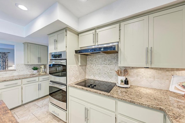 4113 Rimrock Dr, Lago Vista, TX 78645 - kitchen with light stone counters, stainless steel double oven, black electric cooktop, under cabinet range hood, and backsplash