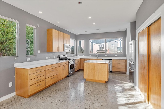 kitchen with a center island, stainless steel appliances, recessed lighting, light countertops, and a sink