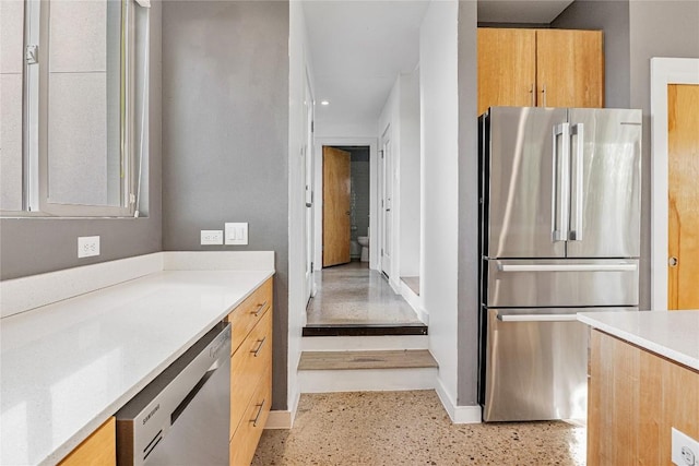 kitchen featuring baseboards, appliances with stainless steel finishes, light countertops, and light speckled floor