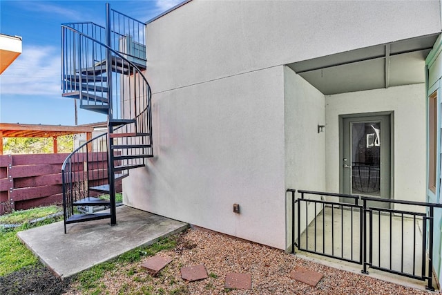 doorway to property featuring fence and stucco siding