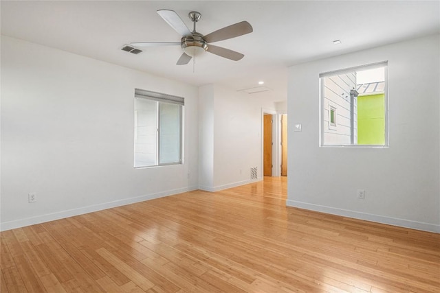 empty room featuring light wood-style floors, visible vents, baseboards, and a ceiling fan