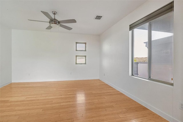 unfurnished room featuring light wood finished floors, visible vents, and a healthy amount of sunlight