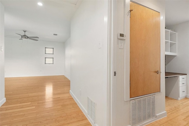 corridor with light wood finished floors, baseboards, and visible vents