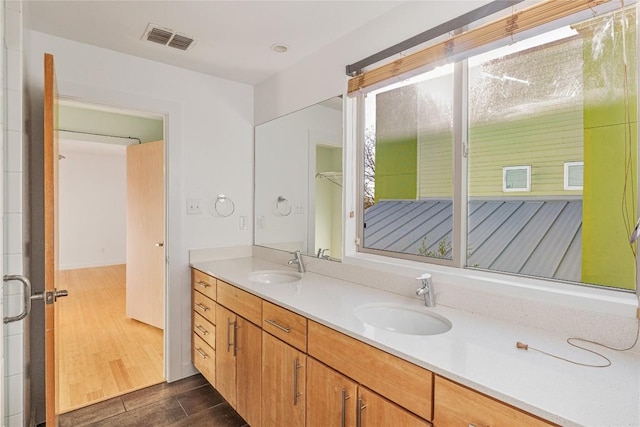 bathroom with double vanity, visible vents, a sink, and wood finished floors