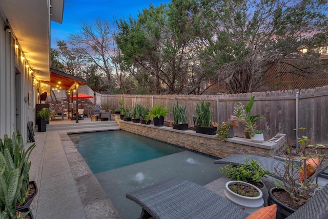 pool at dusk featuring a patio, a fenced backyard, and a fenced in pool