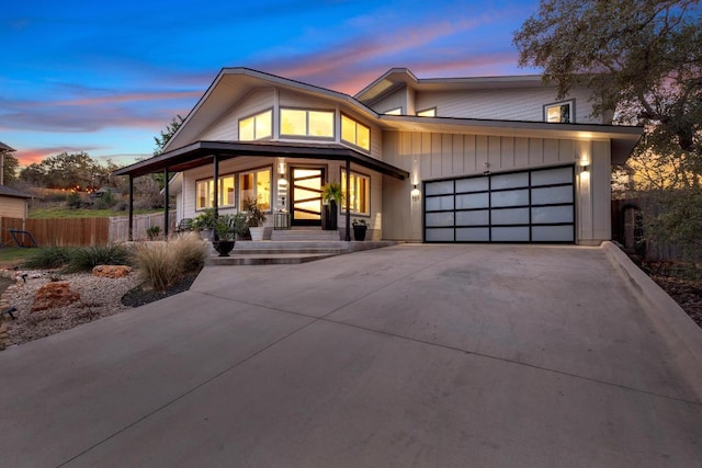 view of front of house with board and batten siding, concrete driveway, a garage, and fence