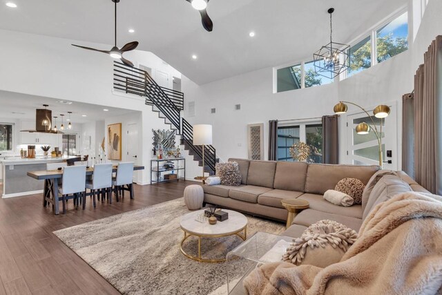 living room with stairway, vaulted ceiling, recessed lighting, ceiling fan with notable chandelier, and wood finished floors