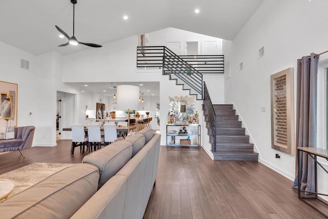 living area with visible vents, high vaulted ceiling, dark wood finished floors, stairway, and ceiling fan