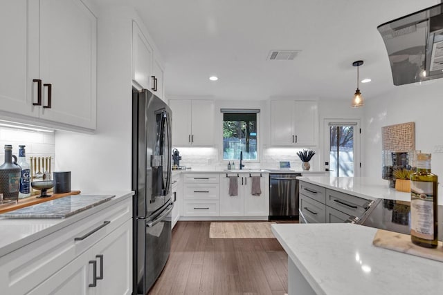 kitchen featuring a wealth of natural light, visible vents, dishwasher, and freestanding refrigerator