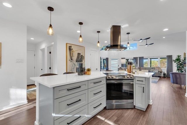 kitchen with dark wood finished floors, stainless steel electric stove, island exhaust hood, light countertops, and open floor plan