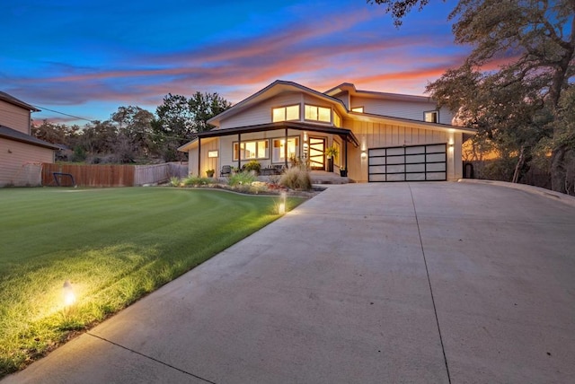 view of front facade featuring concrete driveway, fence, a garage, and a front lawn