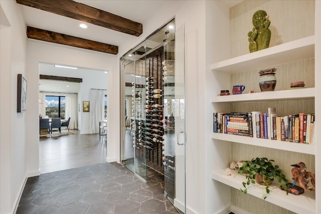 wine room featuring built in features, beam ceiling, and baseboards