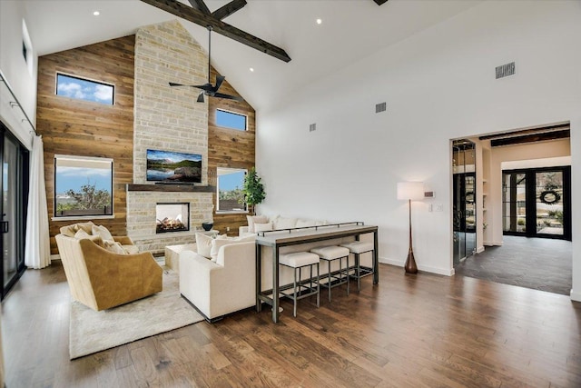 living room with visible vents, dark wood finished floors, a fireplace, high vaulted ceiling, and beam ceiling