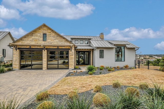 view of front facade with metal roof, a garage, fence, decorative driveway, and a standing seam roof