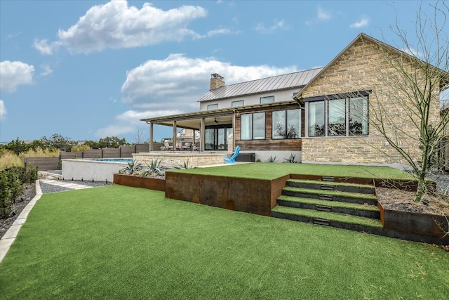 back of house with an outdoor pool, metal roof, a standing seam roof, a yard, and a patio area