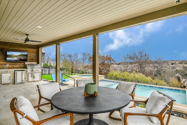 view of patio featuring a fenced backyard, an in ground hot tub, exterior kitchen, a fenced in pool, and outdoor dining space