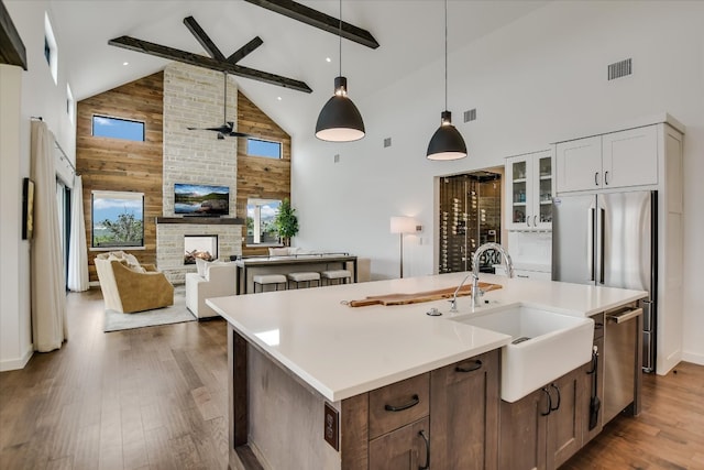 kitchen with a sink, a multi sided fireplace, visible vents, beamed ceiling, and dark wood finished floors